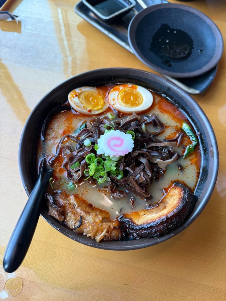 Bowl of ramen with soft-boiled egg, pork, and fresh toppings